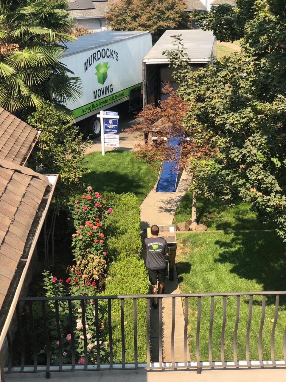 Aerial view of a Murdock's Moving box truck and crew member working a residential move with garden and pool
