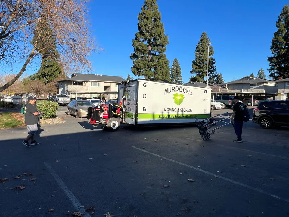 Murdock's Moving & Storage branded MOD portable storage container being positioned in an apartment lot by two crew members