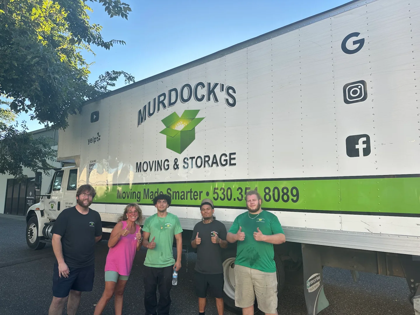 Murdock’s moving crew with a happy client beside a branded truck